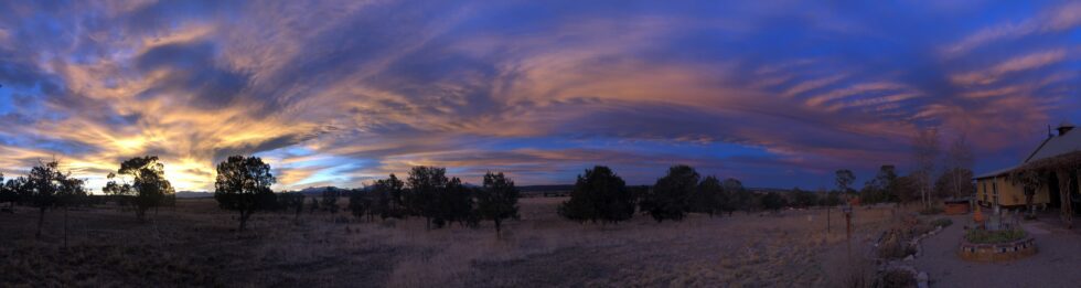 A panoramic view of fields and trees during a sunset